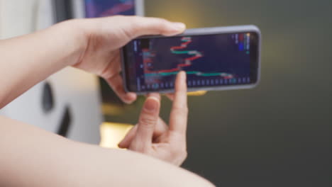 Vertical-video-of-Woman-examining-chart-candles-in-stock-market.